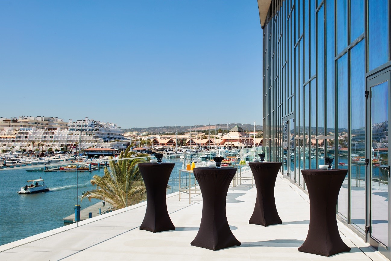 the balcony of the Algarve Congress Center with talll tables overlooking the harbour of Vilamoura